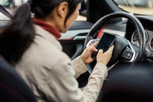 Selective focus on an Asian woman's hands typing on her phone while she sits in her car. 
