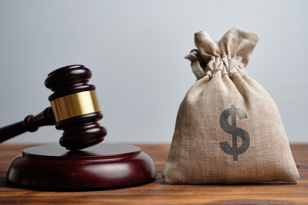 Judge’s gavel next to money bag with dollar sign