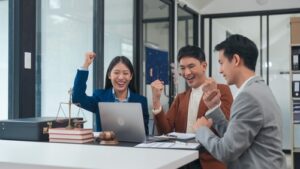 Three excited plaintiffs celebrating with their lawyer in an office, symbolizing the successful pursuit of justice in a mass tort lawsuit