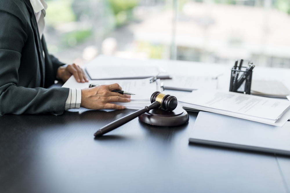 Lawyer reviewing legal documents at desk with gavel in office.