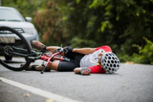 Severe road rash injury on a cyclist’s leg showing deep wounds and bandages after a bicycle accident.
