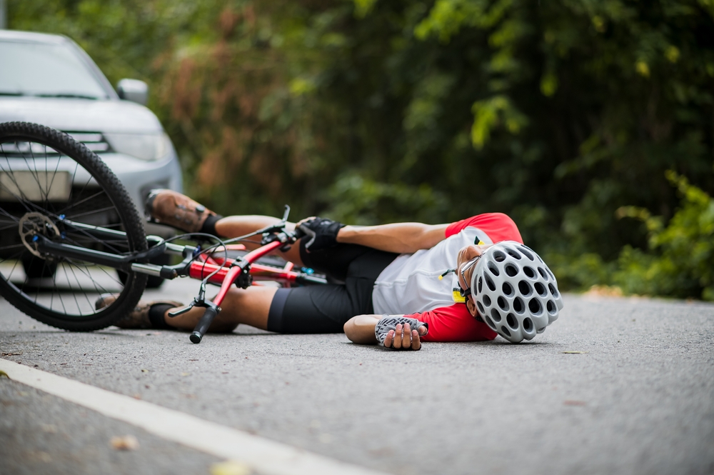 Severe road rash injury on a cyclist’s leg showing deep wounds and bandages after a bicycle accident.