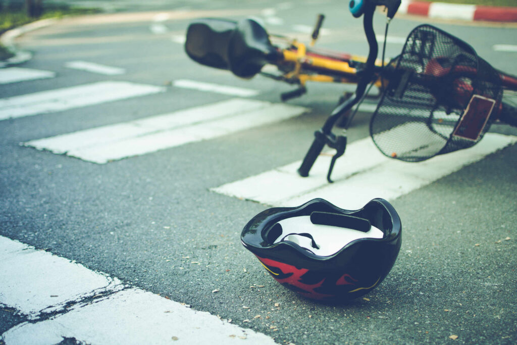 A bicycle helmet and fallen bike on a crosswalk, illustrating a crash case handled by Boca Raton Bicycle Accident Lawyers.