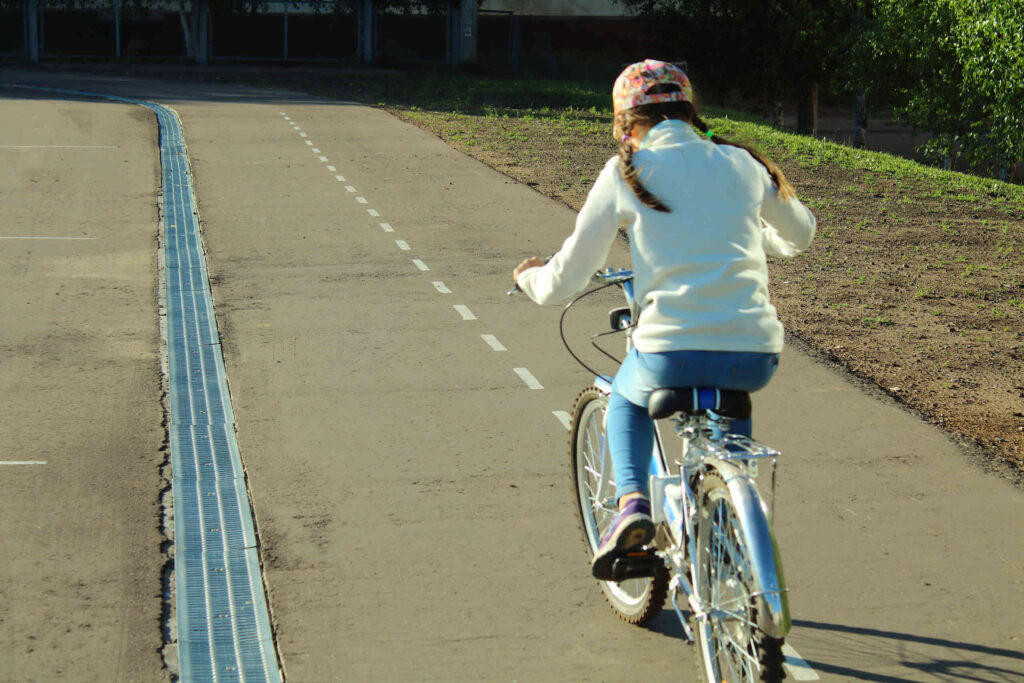 A person riding a bicycle down a paved path, illustrating commuter safety and pedestrian right-of-way laws in Boca Raton.