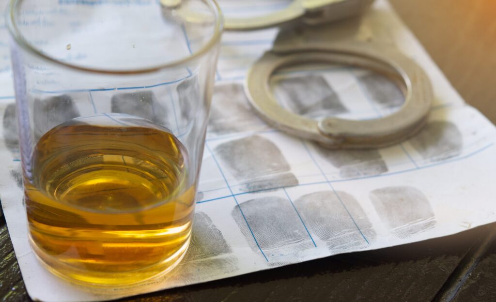 An alcoholic drink next to handcuffs and fingerprints, illustrating a DUI injury lawsuit represented by Boca Raton Bicycle Accident Lawyers.