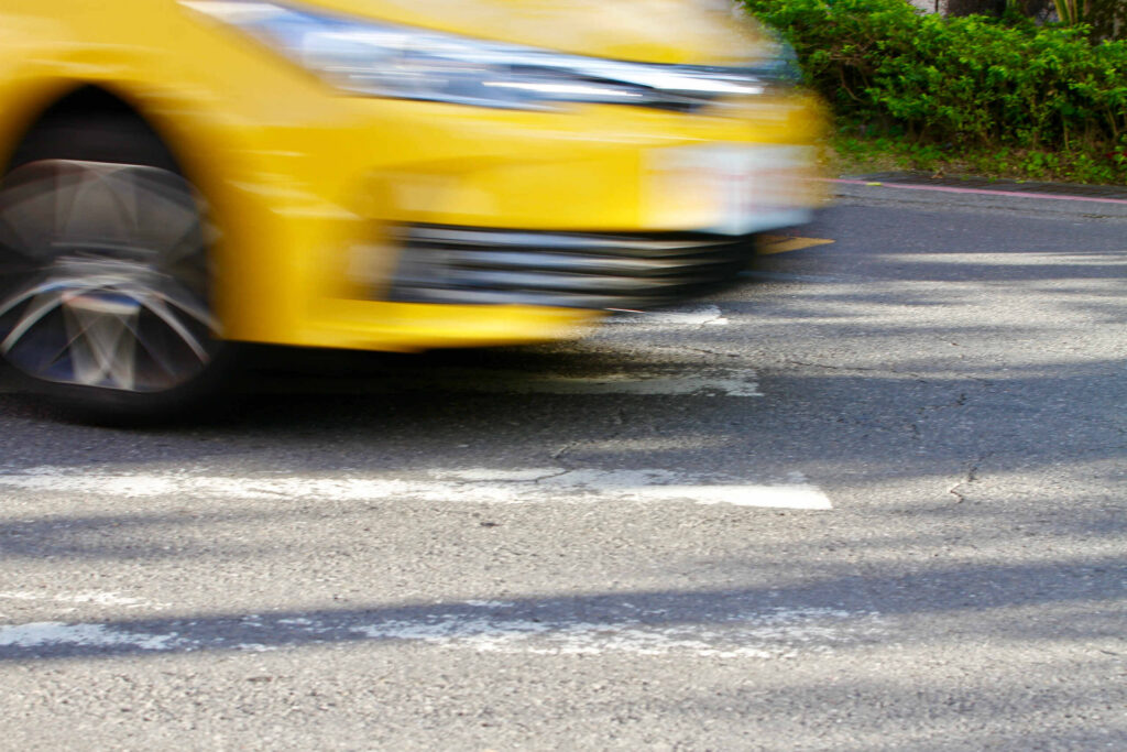 A blurry yellow car speeding through a crosswalk, highlighting reckless driving cases handled by Boca Raton Bicycle Accident Lawyers.