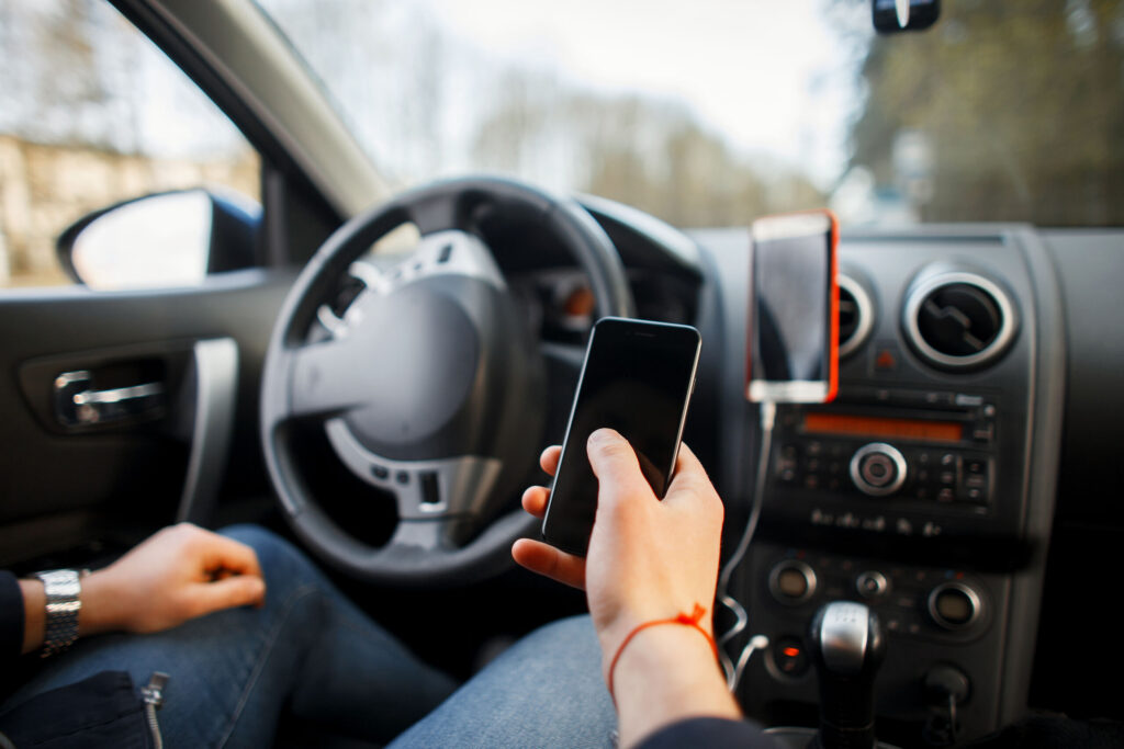 A driver holding a smartphone inside a car, illustrating rideshare accident evidence to collect in Boca Raton.