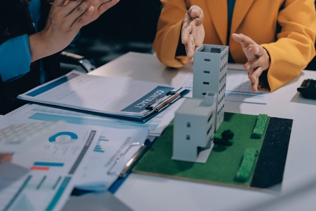 Legal advisors discussing property contracts and model buildings alongside Florida timeshare exit and cancellation attorneys.